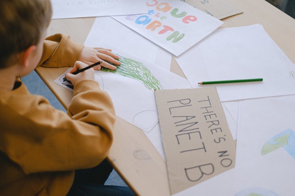 boy-drawing-at-a-desk-11286137 A child creates eco-friendly posters promoting environmental awareness.