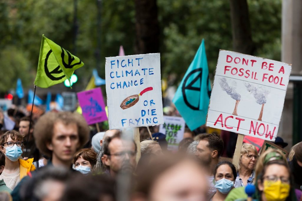 crowd-protesting-against-climate-policy-9729883 Crowd of diverse individuals at a climate change protest displaying impactful banners and flags outdoors.